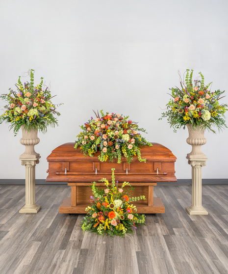 Sympathy suite with roses, hydrangeas, protea, and feathers in earthy tones.